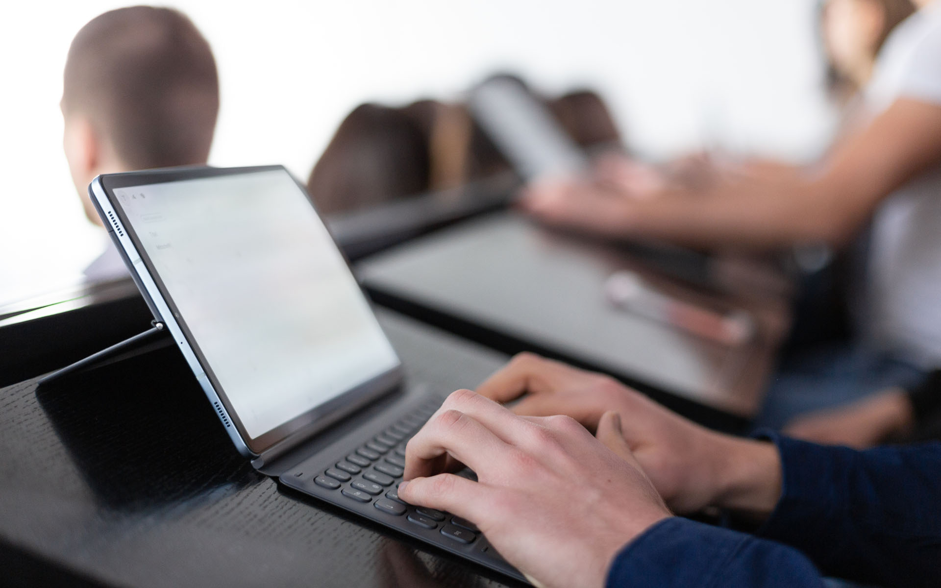 Close up of tablet with keyboard in classroom with students