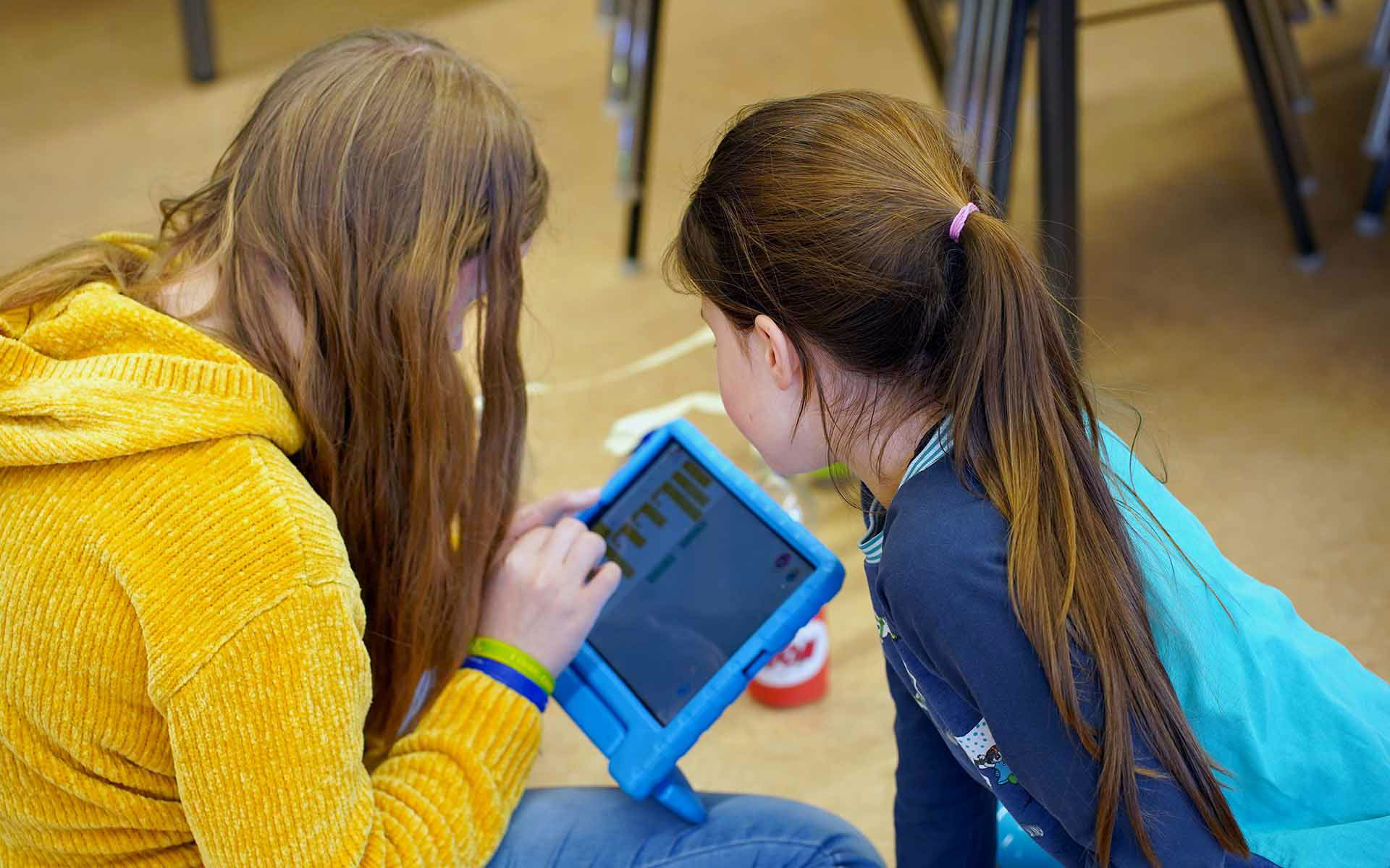 Zwei junge Mädchen spielen mit einem Tablet.